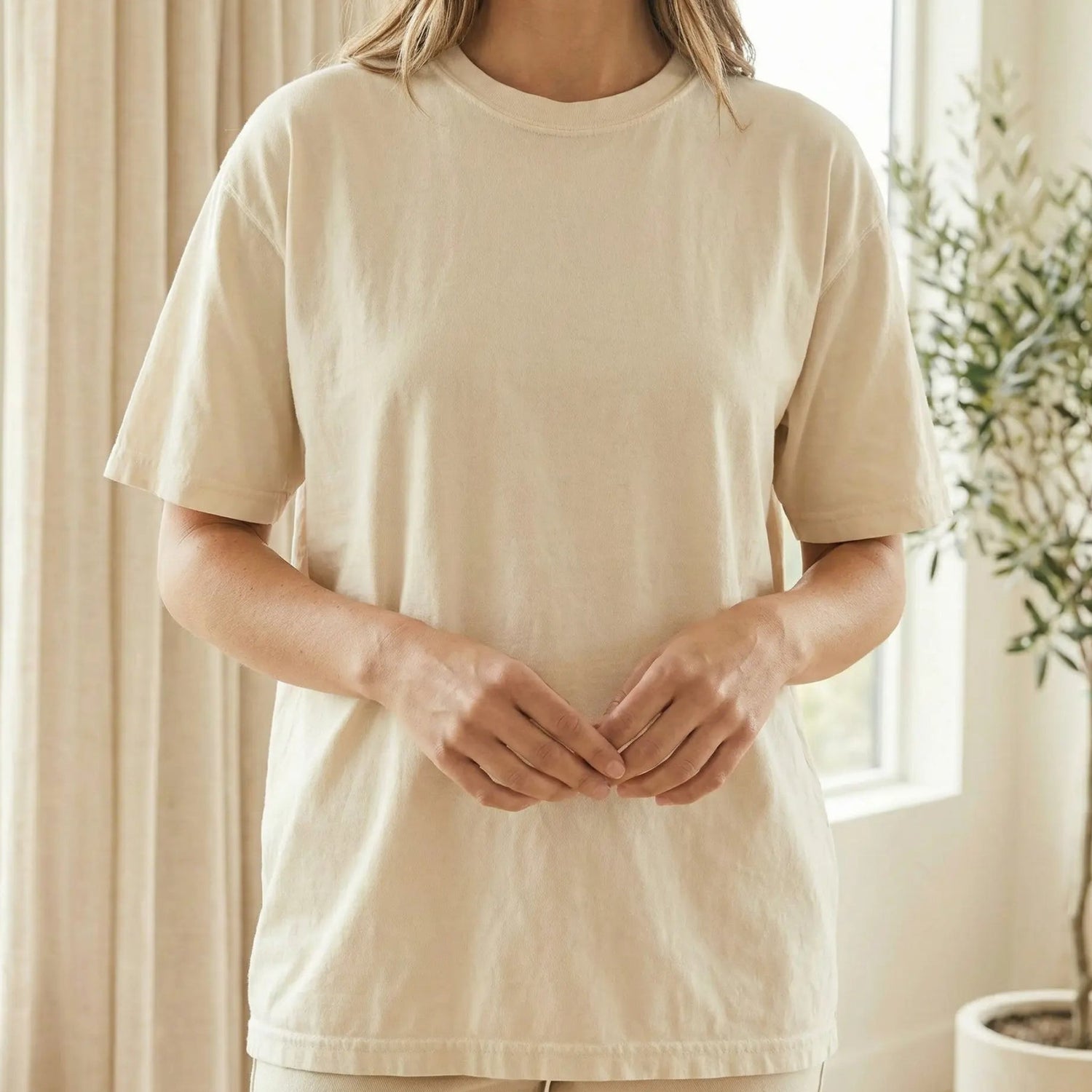 Person wearing cream minimalist t-shirt in calm neutral setting